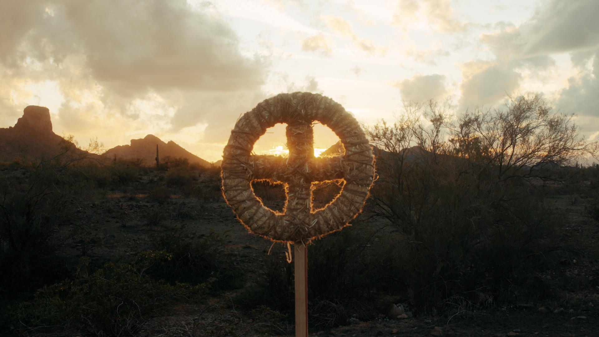 Straw wreath shaped like a sun cross on a wooden pole in the desert at sunset